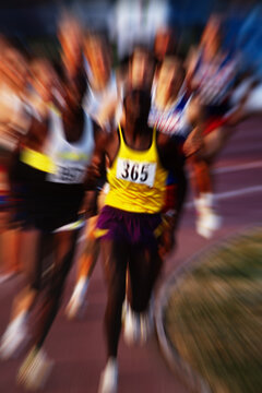 Vintage 35mm film scan of long distance track race with zoom blur, group of runners on stadium track, grainy analog sports photography.