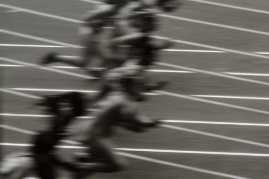 High-energy action shot of sprinters exploding from starting blocks on track. Authentic 35mm reversal film scan, motion blur effect, grainy analog sports photography.