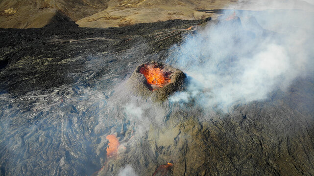 Aerial view of fiery lava erupts from a volcanic cone, as smoke billows against the stark landscape, creating a dramatic display of nature's raw power, Grindavik, Iceland.