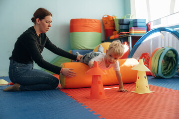 Exercises for motor skills. Preschool child with teacher during developmental activities in a playroom