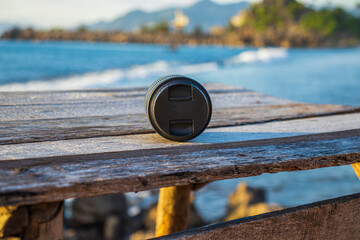 Camera Lens on Wooden Table by the Sea in the Afternoon &ndash; Travel Photography and Creative Outdoor Lifestyle Concept