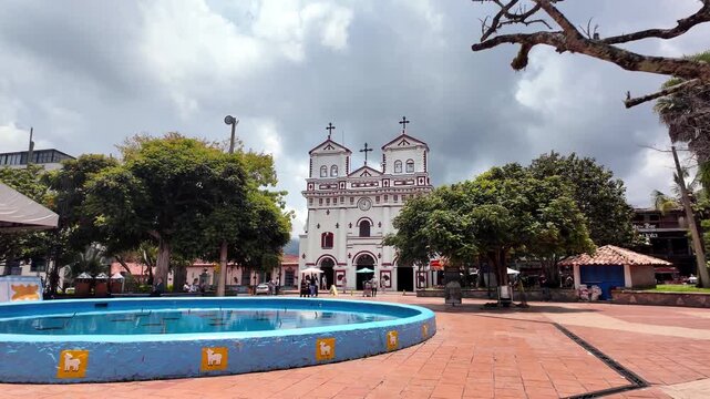 Experiential POV Walking Shot Through Guatape Main Square (Parque Principal) Directly Facing the Historic White Nuestra Se&ntilde;ora Del Carmen Church.