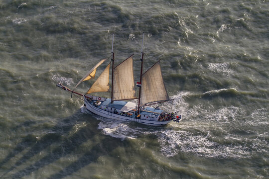 Hook of Holland, Netherlands - 11 February 2026: Aerial view of a majestic sailing ship braving the choppy, sun-kissed waves of the North Sea.