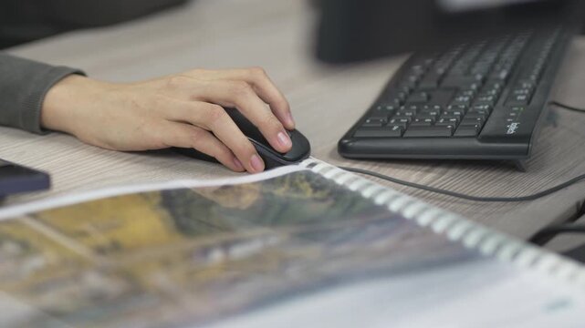 Elegant female hand with delicate manicure rests on smooth computer mouse. Calm office setting highlights controlled digital interaction