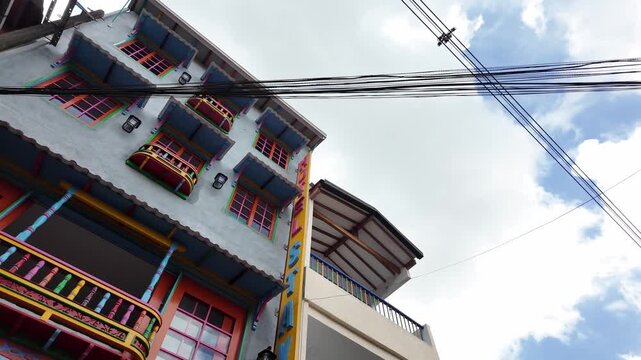 Vibrant upward view of a historic Spanish colonial building facade featuring colorful traditional balconies (balcones) in Guatape, Colombia.