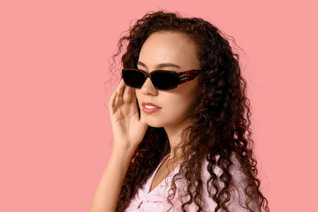 Fototapeta premium Beautiful young African-American woman in sunglasses on pink background
