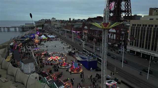 Dusk illuminates the vibrant rides and excitement of Blackpool's seaside amusement park and pier