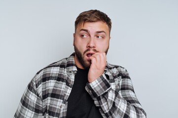 Obraz premium Young man showing surprise while biting his nails in a casual indoor setting