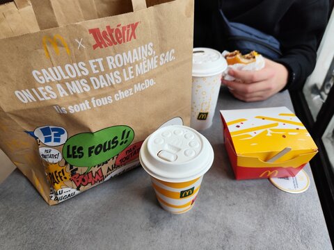 France, Paris - October 29, 2025: Mcdonald order on table. Asterix package. Glass drink burger potatoes. Food set Menu in McDonalds cafe French language.