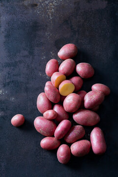 Sliced and whole red baby potatoes on rusty metal