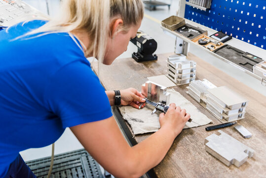 Woman measuring metal workpiece