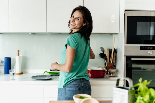 Portrait of smiling woman cooking in kitchen