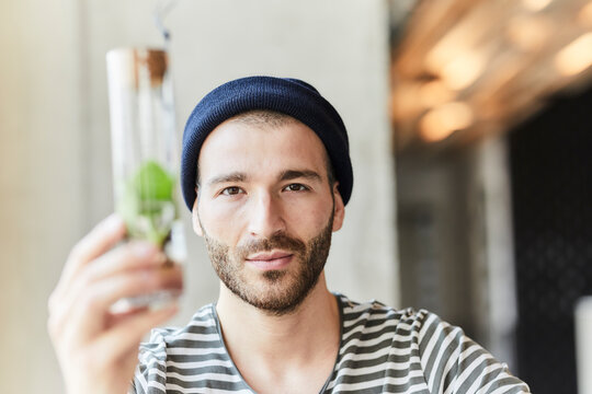 Portrait of young man holding plant in a jar
