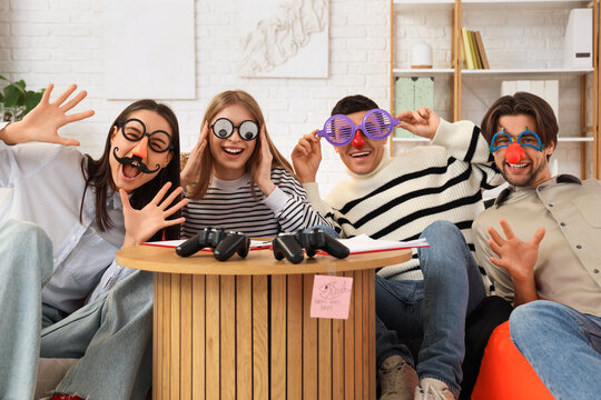 Happy business colleagues with funny disguise in office. April Fools' Day celebration