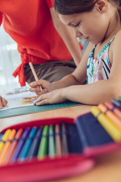 Mother helping girl doing her schoolwork at home