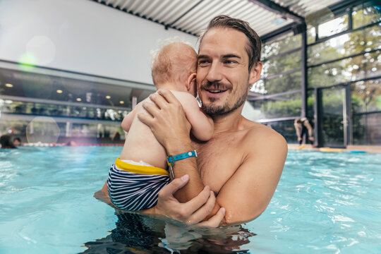 Father holding baby in indoor swimming pool