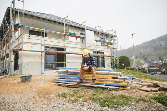 Worker on a construction site having a break checking cell phone