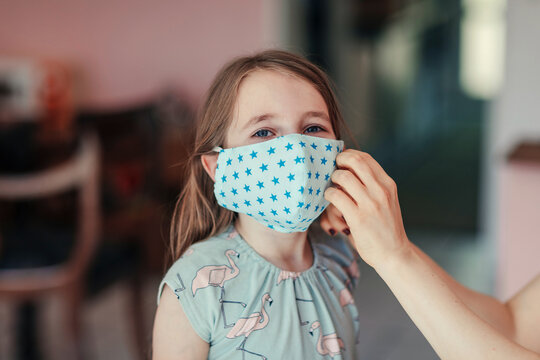 Mother tries mask on daughter's face at home