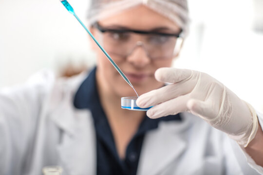 Scientist working in lab with pipet and petri dish