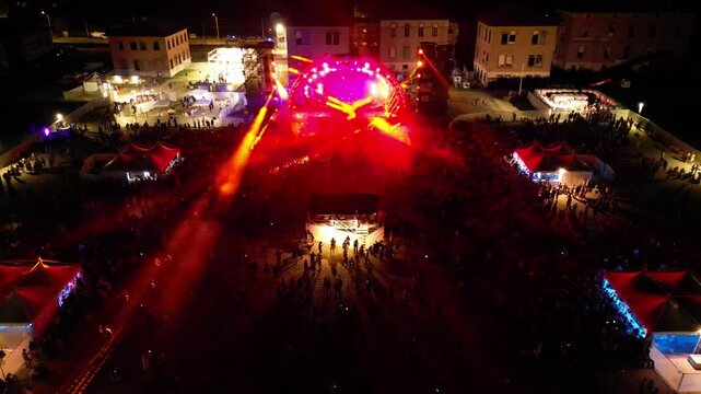 Night Concert Spectacle: An awe-inspiring aerial view captures a vibrant night concert, the stage illuminated with a kaleidoscope of lights, drawing a bustling crowd into a shared experience.