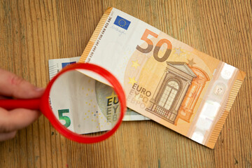 Euro banknotes under a magnifying glass. The concept of inflation, poverty, economic crisis. The concept of saving money. Finance, business, investment. Saving savings at home. 