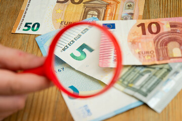 Euro banknotes under a magnifying glass. The concept of inflation, poverty, economic crisis. The concept of saving money. Finance, business, investment. Saving savings at home. 