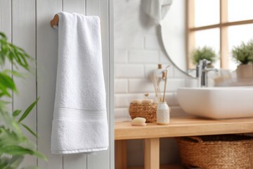 Close up of soft white towel hanging on metal holder against gray textured bathroom wall, showcasing clean modern home interior.