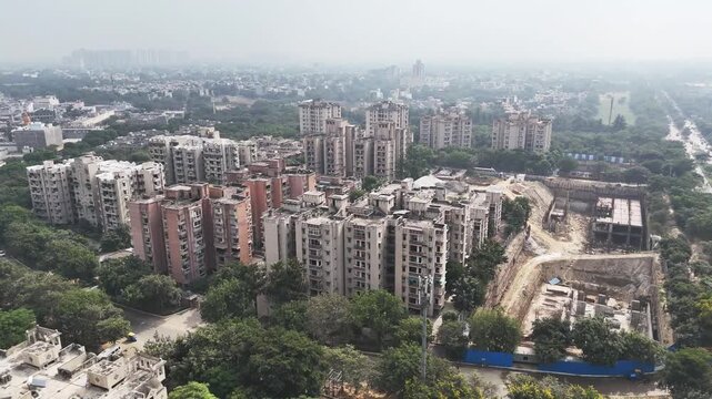 Drone footage capturing rapid development: a sprawling construction zone surrounded by planned apartments housing, greenery, and the evolving skyline of NCR.