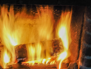 close of a roaring log fire with warm yellow flames and charred log 