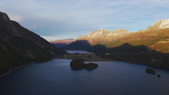 Alpine Lake Sils with golden light on the mountains in Maloja, Swiss Alps. Aerial drone panoramic view. Copy space