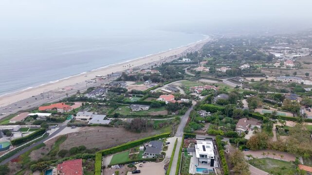 Aerial Flyover Of Wealthy Hilltop Waterfront Mansions Overlooking Zuma Beach In Malibu, California, USA.