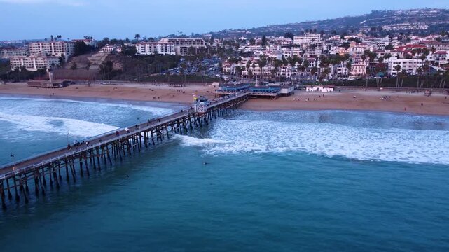 Long Coastal Pier in San Clemente California with Nice Pink Sunset. Wide shot pushes in to waves rolling into the beach.