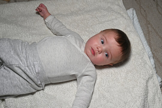 baby lying on its back on a white blanket
