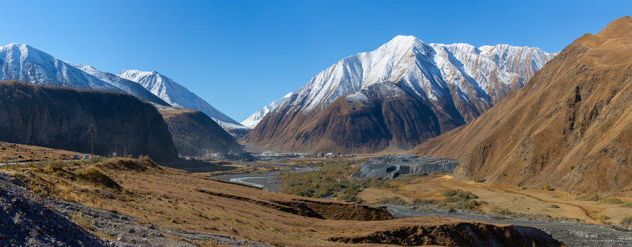 A view of a mountain valley surrounded by snow-capped mountains in the Caucasus