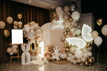 Festive screen photo backdrop for a family photo shoot at a holiday in a restaurant decorated with balloons, neon signs, soft toys and a large butterfly