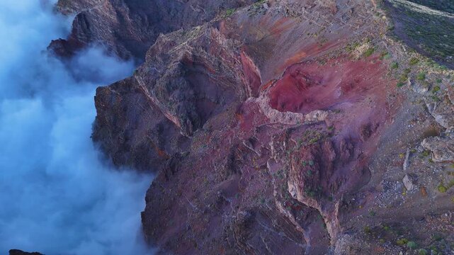 Aerial drone footage pulling away from mountain ridge above clouds in Roque de los Muchachos, La Palma