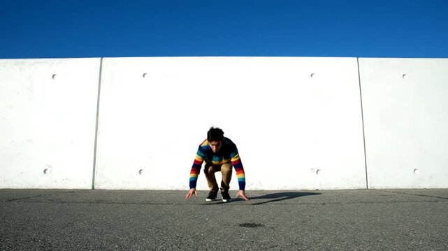 Young man jumps against wall.