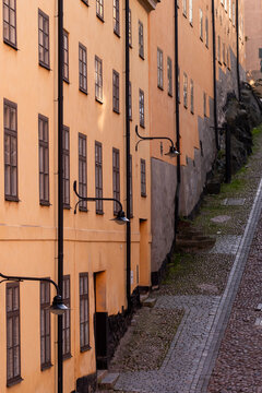 Quiet street of historic facades shows architecture in Stockholm Sodermalm Sweden with an alley perspective and cobblestone path through old buildings