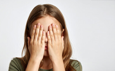 Fototapeta premium Niña tapándose el rostro con las manos, concepto de problemas emocionales y familiares en la infancia, ansiedad infantil, miedo, inseguridad o vergüenza