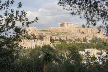 Fototapeta premium Parthenon temple on Acropolis hill in Athens framed by trees. Iconic Greek monument, ancient ruins and popular travel destination.