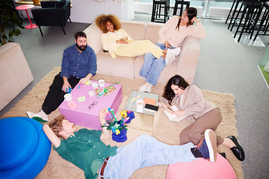 High angle view of male and female business experts relaxing during break time in office lobby