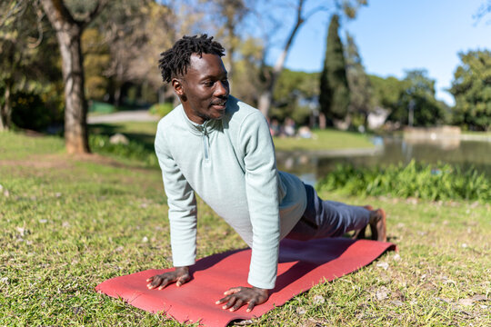 African American man doing yoga outdoors, finding relaxation, wellness, and healthy mind