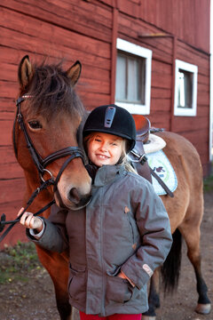 Portrait of smiling girl embracing horse outside stable