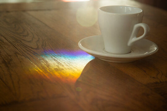 Close-up shot of tea cup on wooden table with rainbow colors