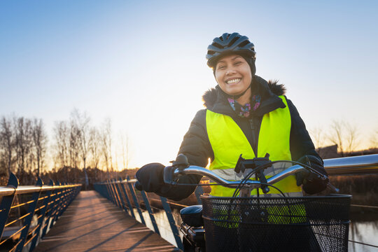 Portrait of smiling woman standing with bicycle on bridge