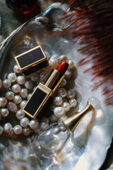 Luxury beauty flat lay: deep red perfume, gold lipstick, black case on iridescent mother-of-pearl tray with natural pearls. Soft dreamy lighting, romantic glow, feminine elegance 