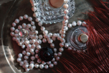 Luxury feminine still life: dark red perfume bottle, gold atomizer, crystal glass , Soft warm lighting, romantic reflections, elegant glamour for beauty, fragrance, and high-end lifestyle concepts.