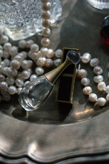 Luxury feminine still life: dark red perfume bottle, gold atomizer, crystal glass , Soft warm lighting, romantic reflections, elegant glamour for beauty, fragrance, and high-end lifestyle concepts.