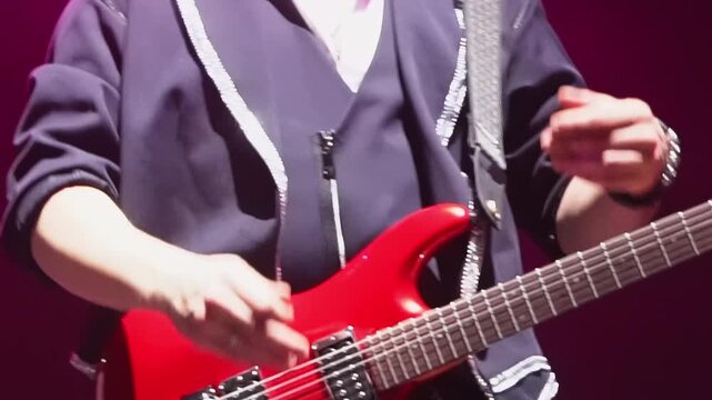 Man with bass guitar claps hands while walks along stage closeup. Positive musician performs with band in night club at festival show