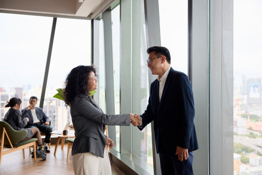 Smiling businessman doing handshake with female colleague at office
